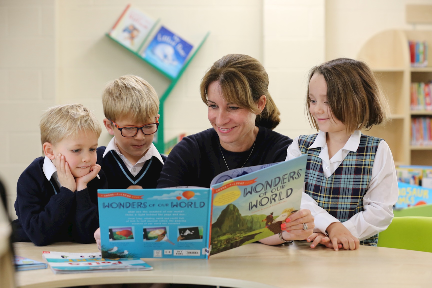 Reception pupils reading a book with a teacher